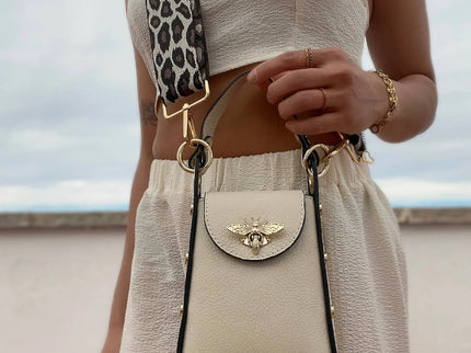 Cream leather crossbody bag with gold bee clasp and leopard strap, styled with chic summer outfit