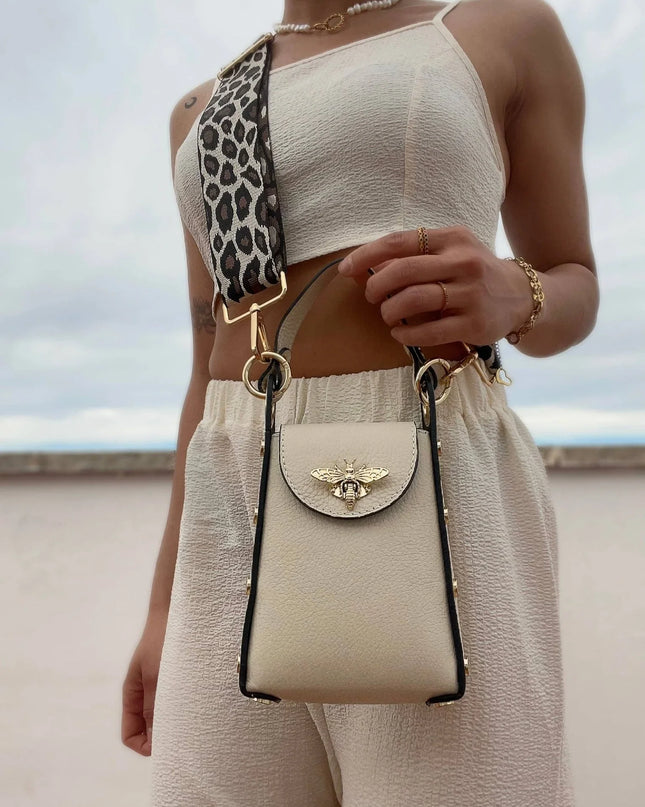 Cream leather crossbody bag with gold bee clasp and leopard strap, styled with chic summer outfit