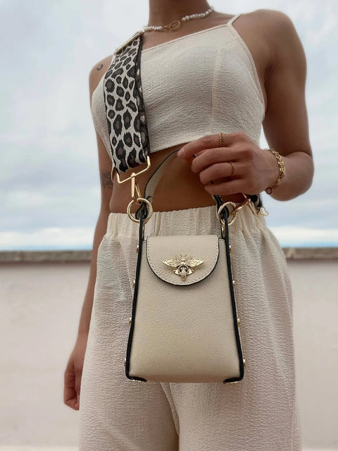 Cream leather crossbody bag with gold bee clasp and leopard strap, styled with chic summer outfit