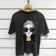 Black graphic tee with stylish woman print, oversized sunglasses, and gold jewelry, hanging on wood hanger