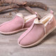 Pink suede slip-on slippers with cozy shearling lining on rustic wood