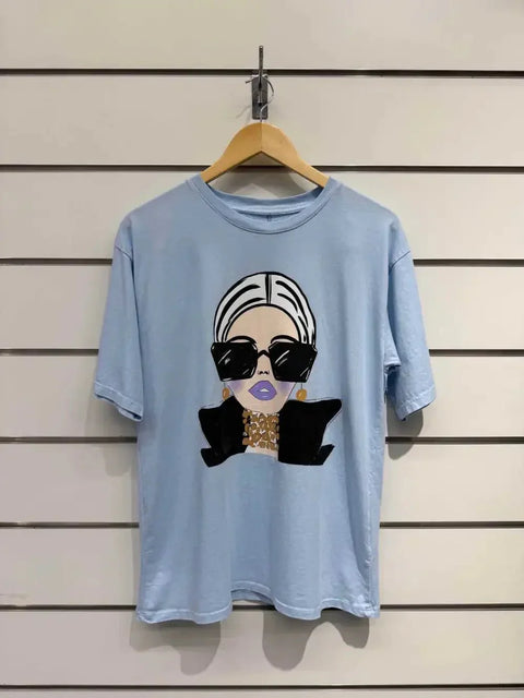Light blue graphic tee with stylish woman print, oversized sunglasses, and gold jewelry, modern fashion design