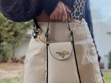 Cream leather crossbody bag with gold bee clasp and leopard strap, styled with navy sweater and mini skirt
