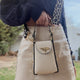 Cream leather crossbody bag with gold bee clasp and leopard strap, styled with navy sweater and mini skirt