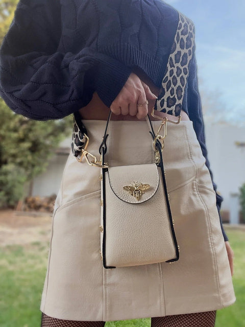 Cream leather crossbody bag with gold bee clasp and leopard strap, styled with navy sweater and mini skirt